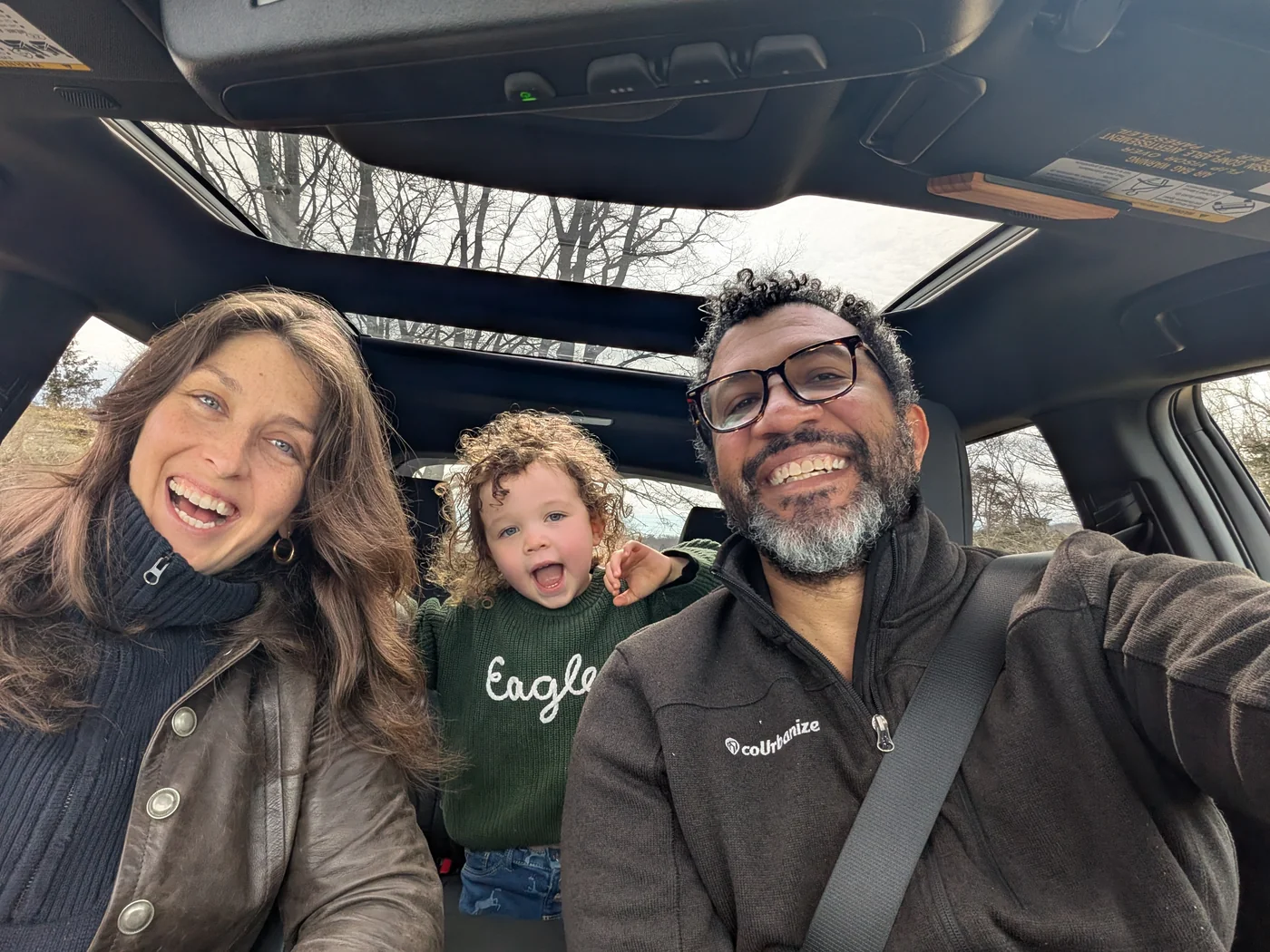 Dan smiling in the car with his wife and daughter.